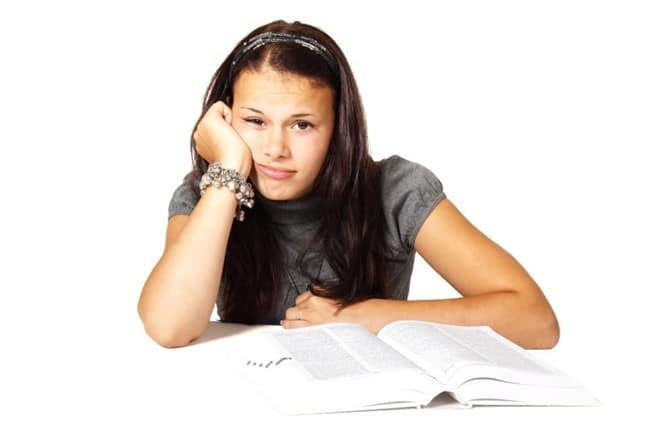 menina com um livro com aparência frustrada